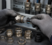 Electrician's gloved hands terminating SWA armoured cable with a brass gland, with additional cable glands and locknuts laid out on a workbench