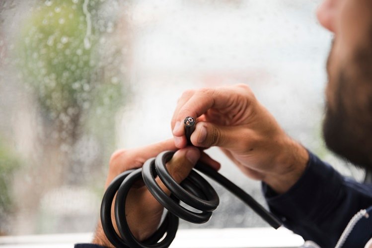 Technician holding a flexible cable Ireland solution, inspecting a durable black electrical cable with exposed internal wiring for industrial and commercial applications.