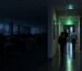 Staff walking towards a fire exit along a corridor lit by green emergency lighting in an office during a power cut in Ireland